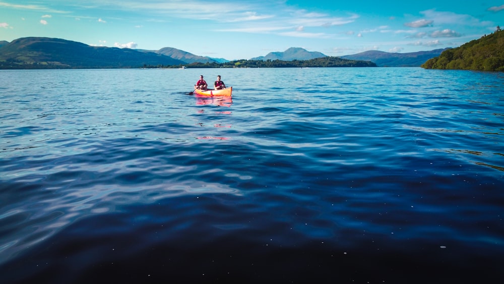 2 people riding on red boat on sea during daytime