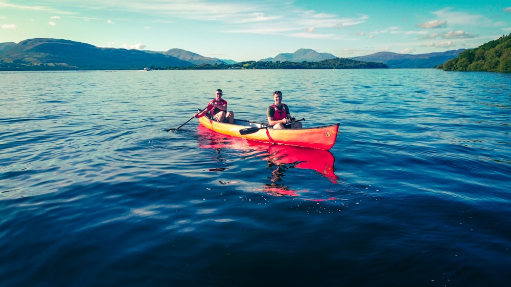 2 person riding on red kayak on blue sea during daytime