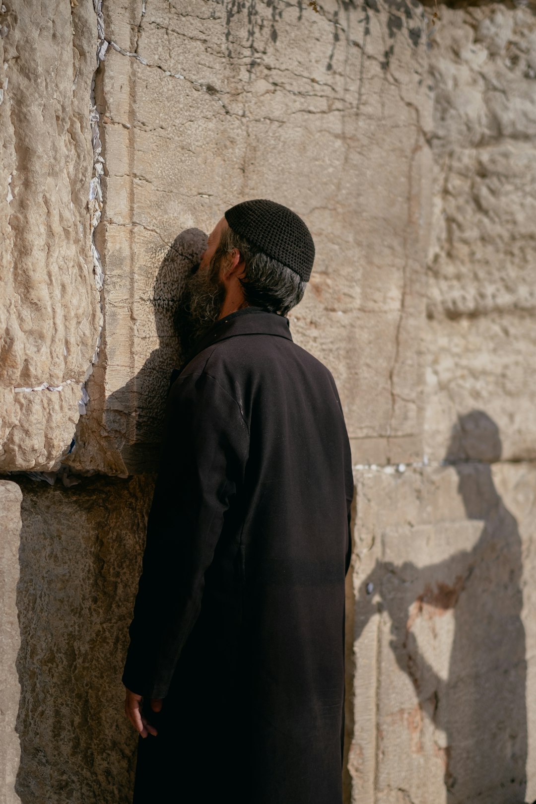 man in black coat standing near brown concrete wall during daytime