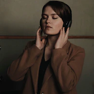 A close-up of a person listening to music with headphones, eyes closed in concentration.