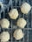 A man proudly presenting a homemade pão de queijo in a rustic kitchen setting.