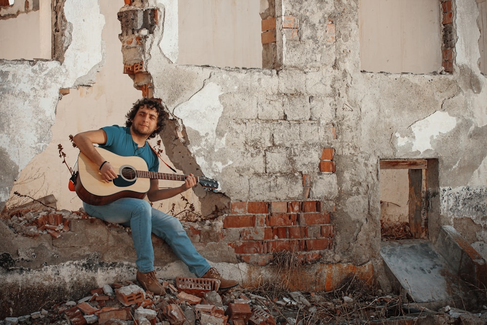 woman in black t-shirt and blue denim jeans playing brown acoustic guitar