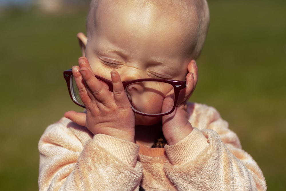 child in white sweater wearing black framed eyeglasses