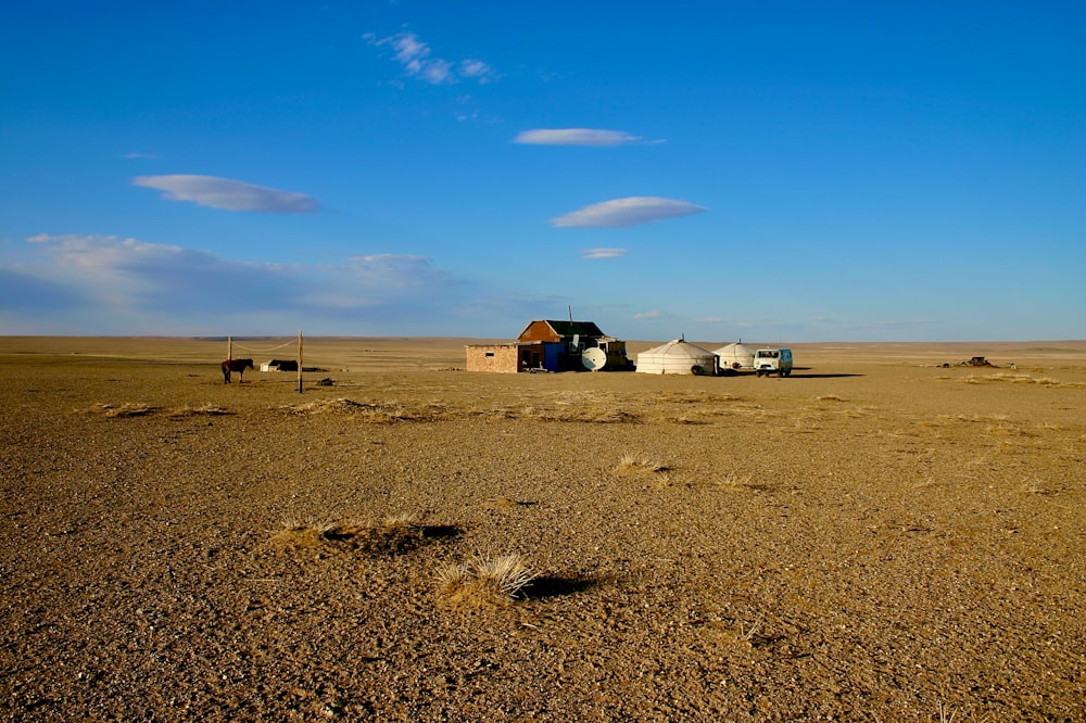 white and brown house on brown sand under blue sky during daytime