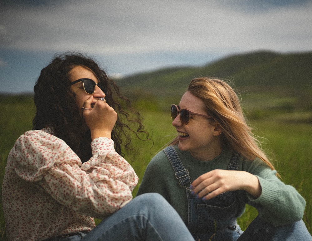 woman in blue denim jacket and blue denim jeans sitting on green grass field during daytime