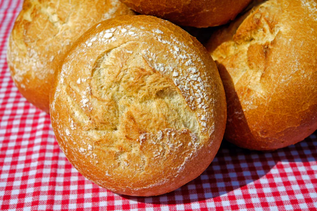 Artisan bread rolls with a crisp crust resting on a cream linen cloth.