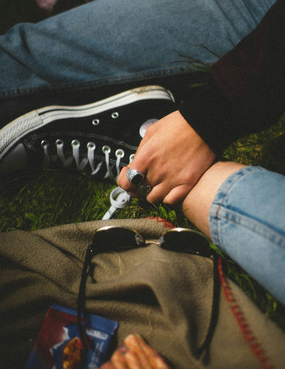 a person sitting on the grass with a pair of scissors in their hand