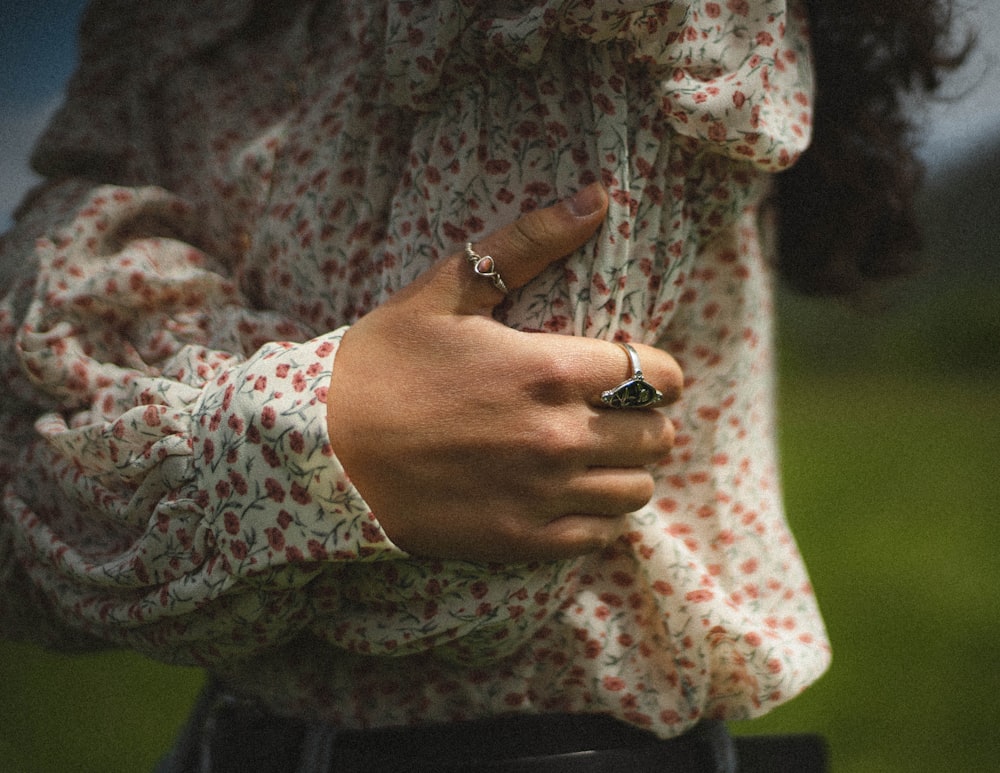woman in white and pink floral long sleeve shirt wearing gold ring