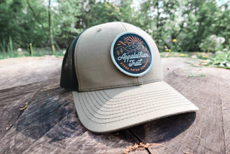 Close-up of a rugged all-terrain active cap with foldable brim and UPF 50+ protection resting on a rocky mountain ledge.