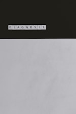 A series of Scrabble tiles spelling out the word 'DIAGNOSIS' is arranged horizontally on a surface. The background is divided, with a dark upper section and a light lower section.