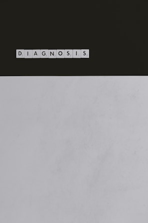 A series of Scrabble tiles spelling out the word 'DIAGNOSIS' is arranged horizontally on a surface. The background is divided, with a dark upper section and a light lower section.