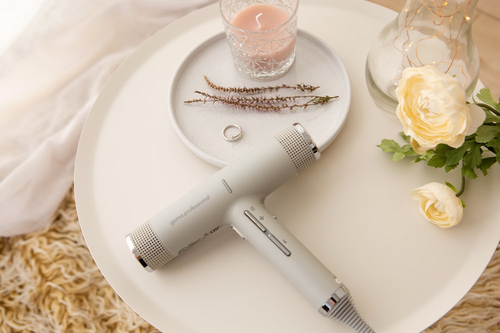 white hair dryer beside clear drinking glass