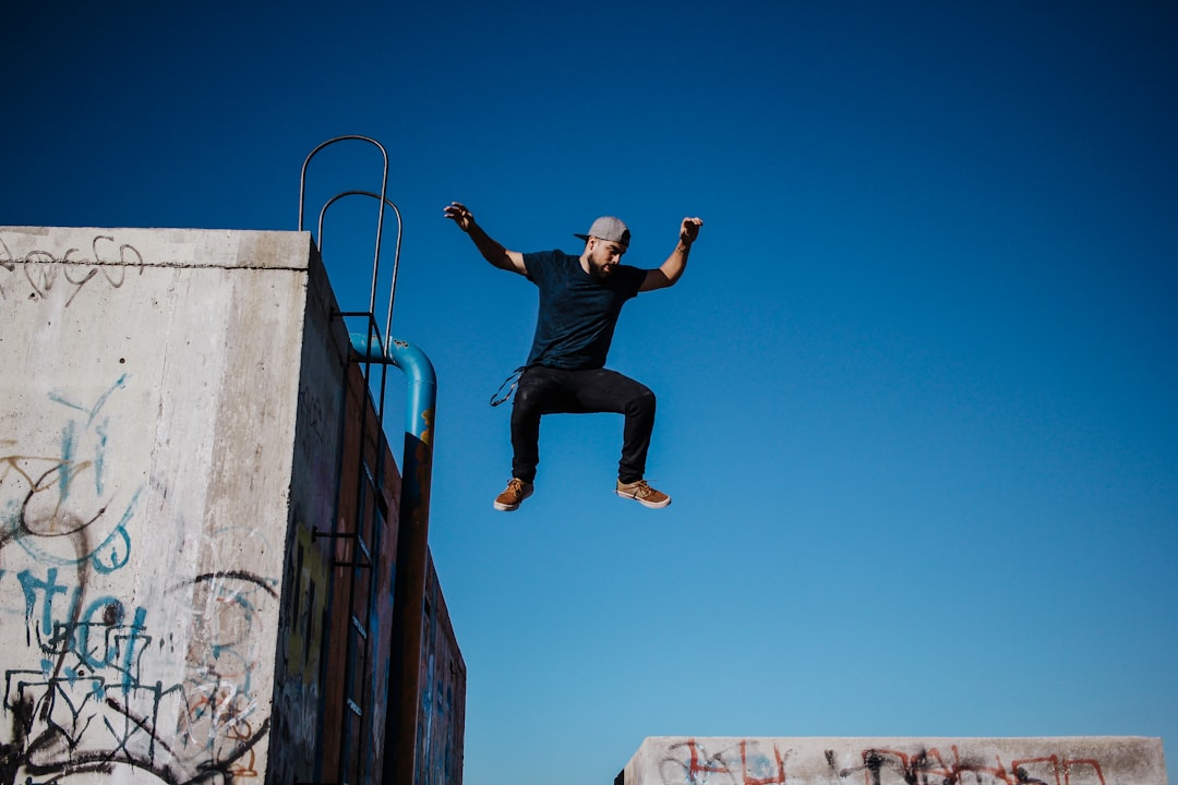 man in black t-shirt and black pants jumping on blue metal railings during daytime