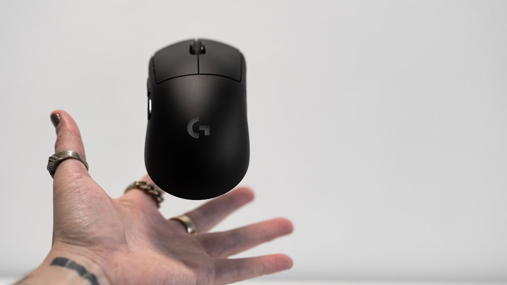 Persona sosteniendo el mouse de computadora inalámbrico Logitech negro