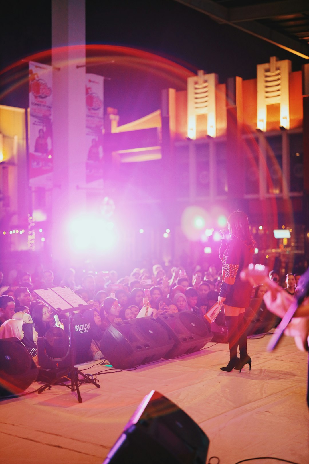 man in red shirt playing guitar on stage