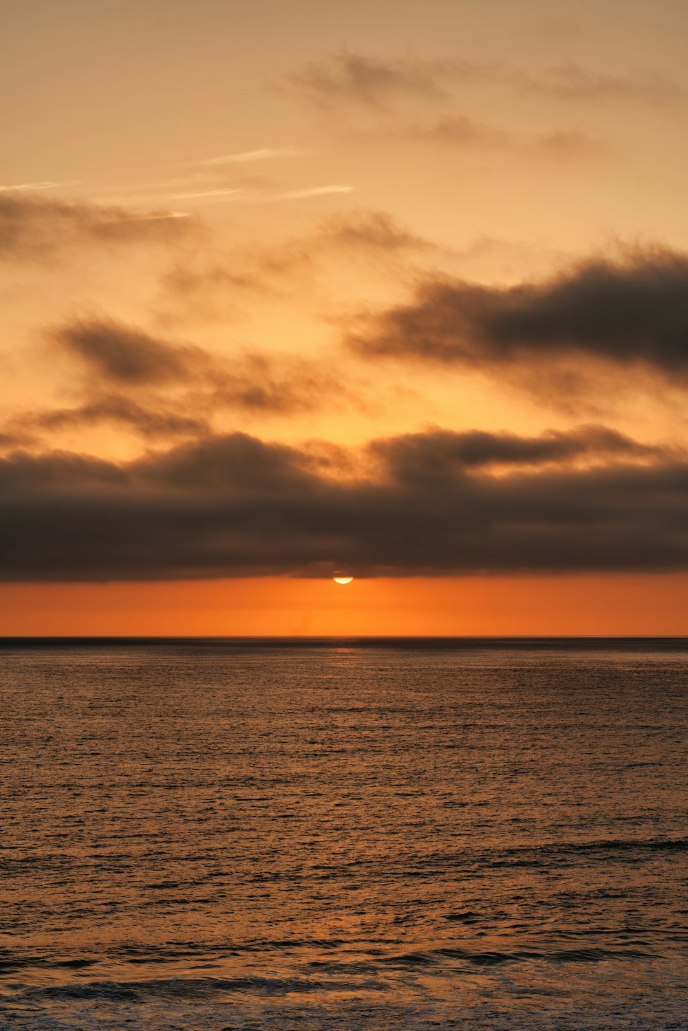 body of water under cloudy sky during sunset