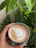 A happy customer holding a vibrant potted plant next to a steaming cup of coffee.