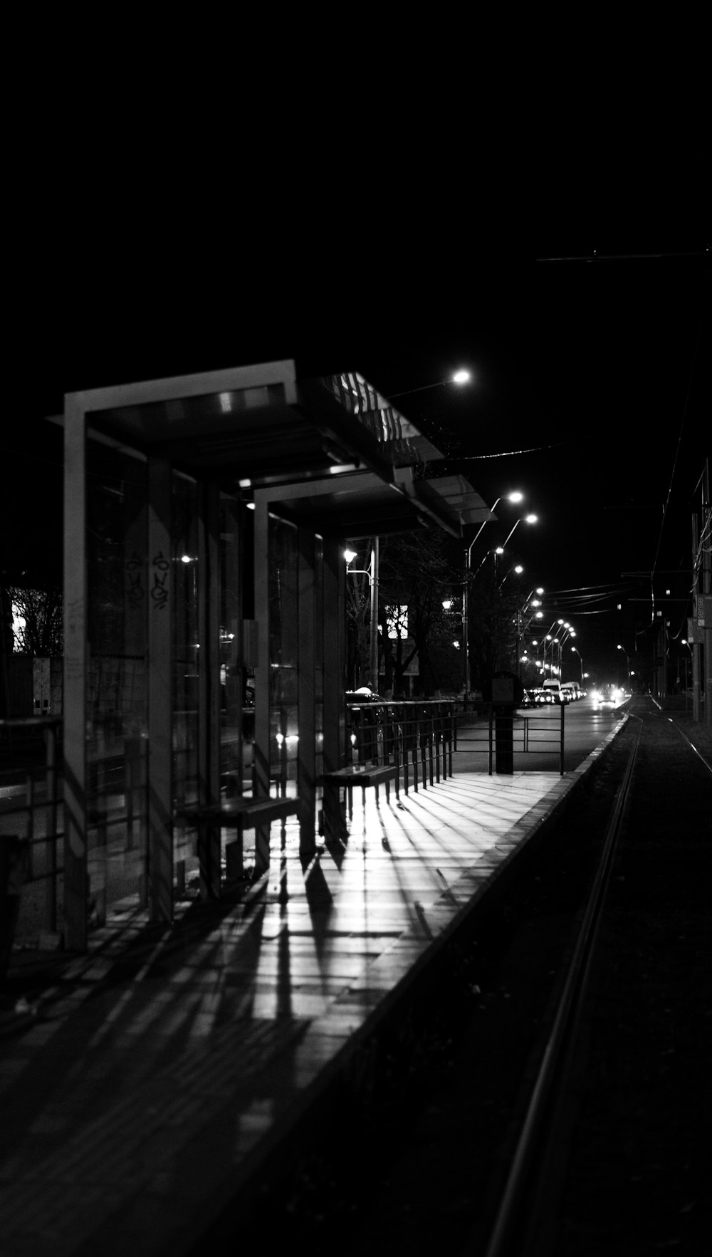 Foto en escala de grises de personas caminando por la acera durante la noche