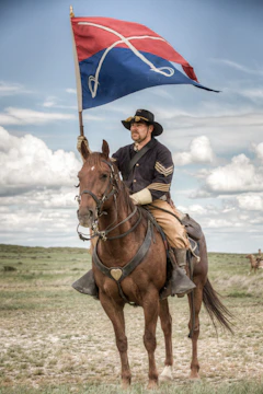Tony dressed in detailed Civil War cavalry uniform, mounted on a horse amid a dusty battlefield scene.