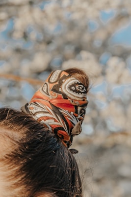Close-up of a vibrant head scarf tied elegantly around a woman's hair, fluttering in the breeze.