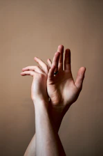 Soft watercolor illustration of intertwined hands glowing with light.