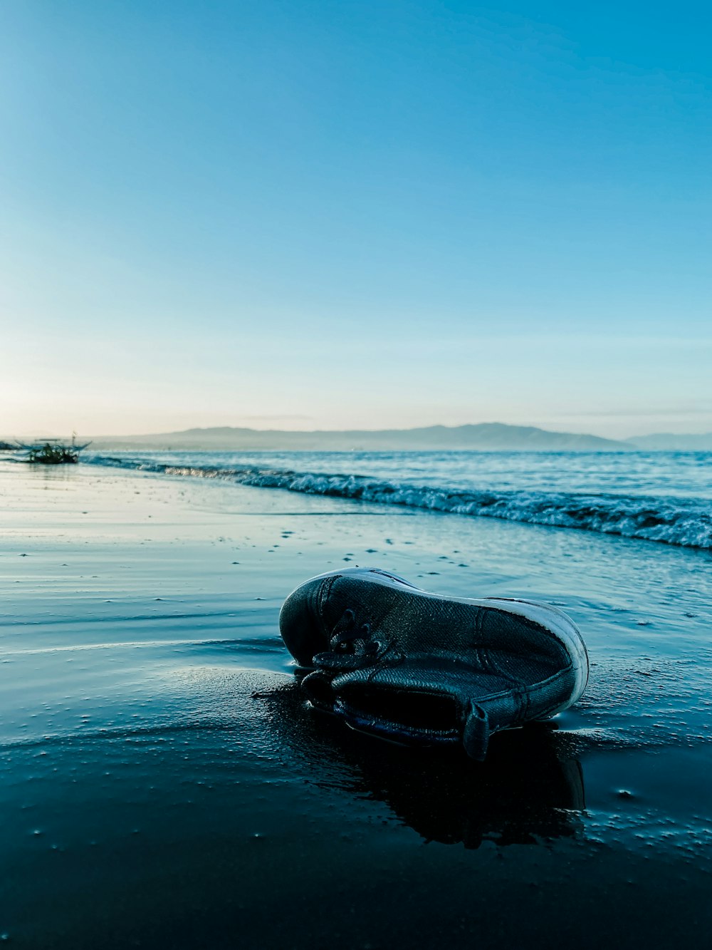 black leather shoe on seashore during daytime