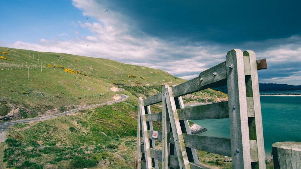 white wooden fence on green grass field near body of water under blue sky during daytime