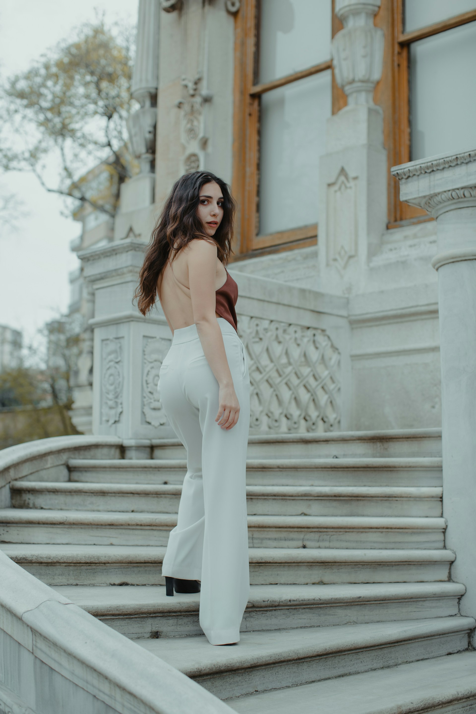 woman in white sleeveless dress standing on stairs during daytime