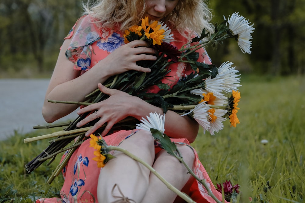 woman in blue and red floral dress sitting on green grass field