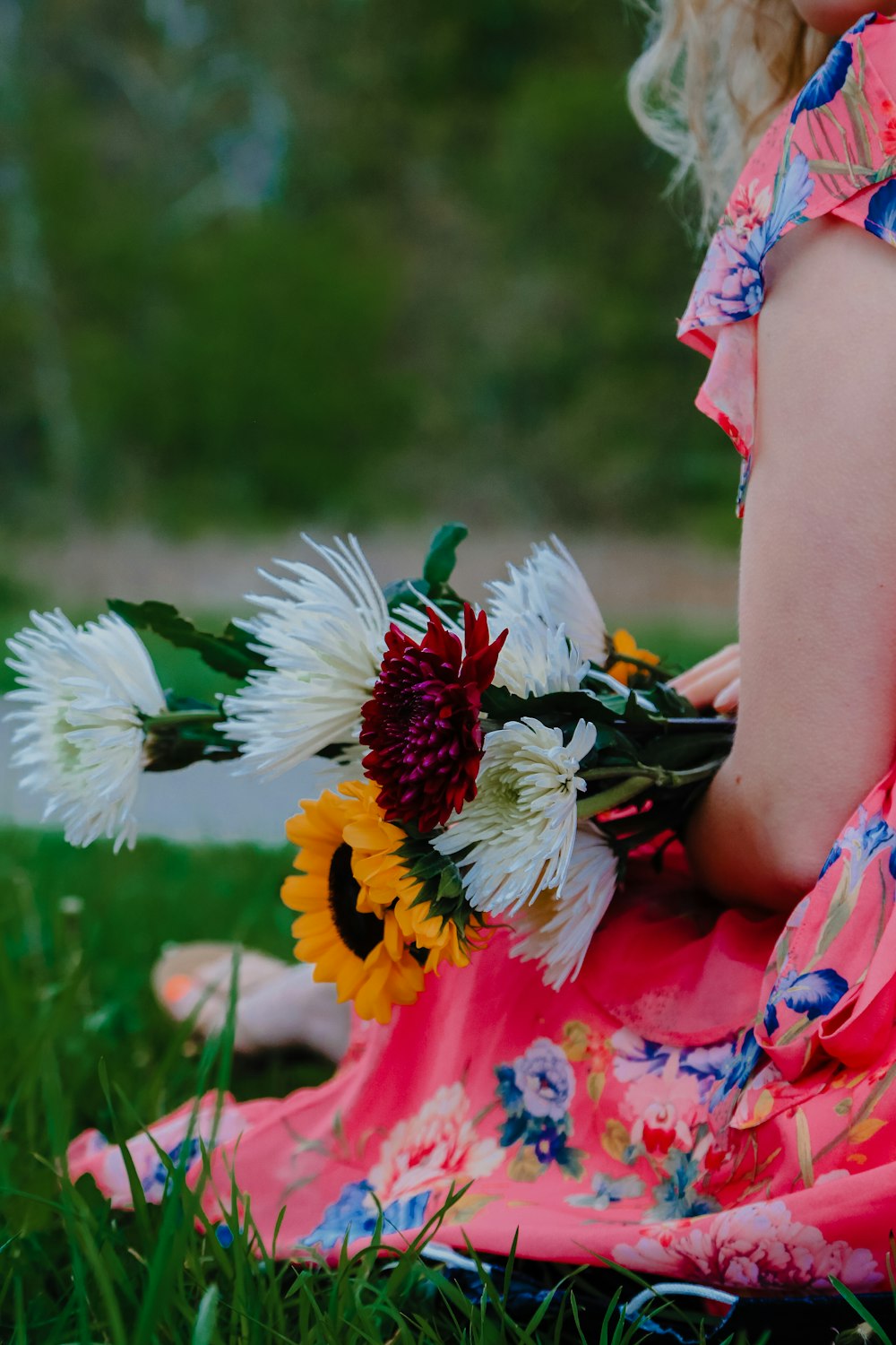 woman in red and white floral dress holding white daisy flowers