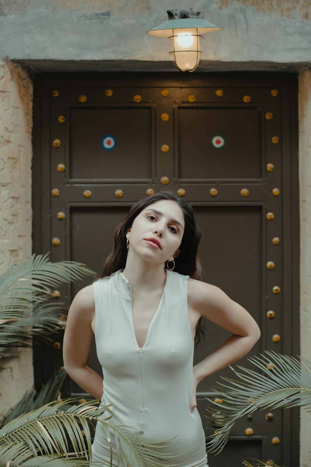 woman in white sleeveless dress standing beside brown wooden door