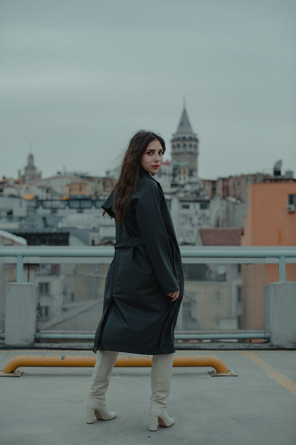 woman in black coat standing on yellow railings during daytime