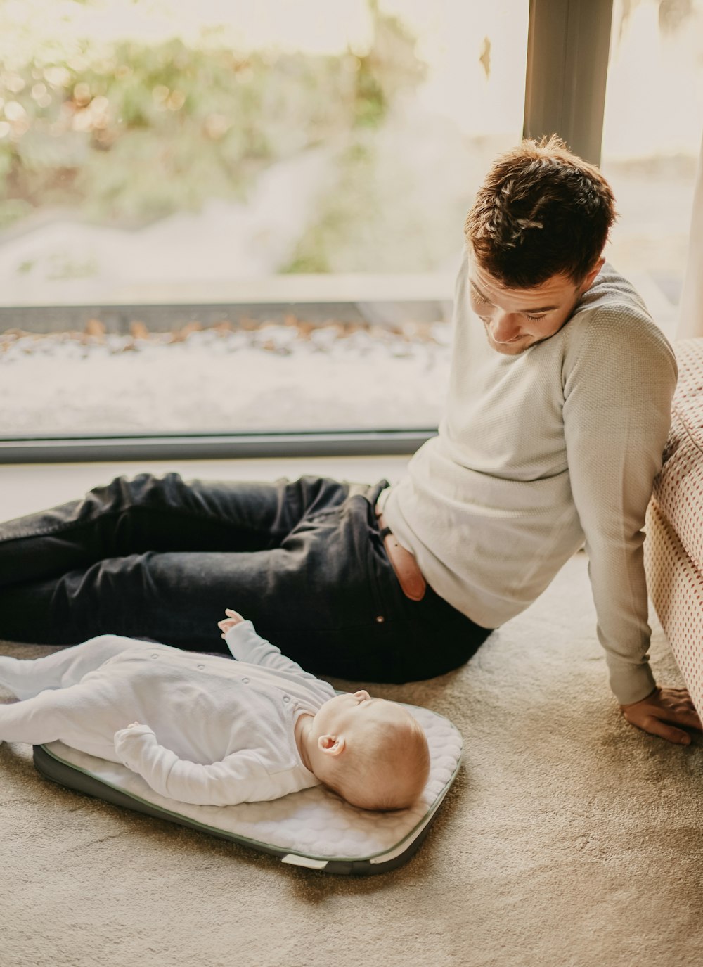 man in gray sweater lying on floor beside man in black shirt