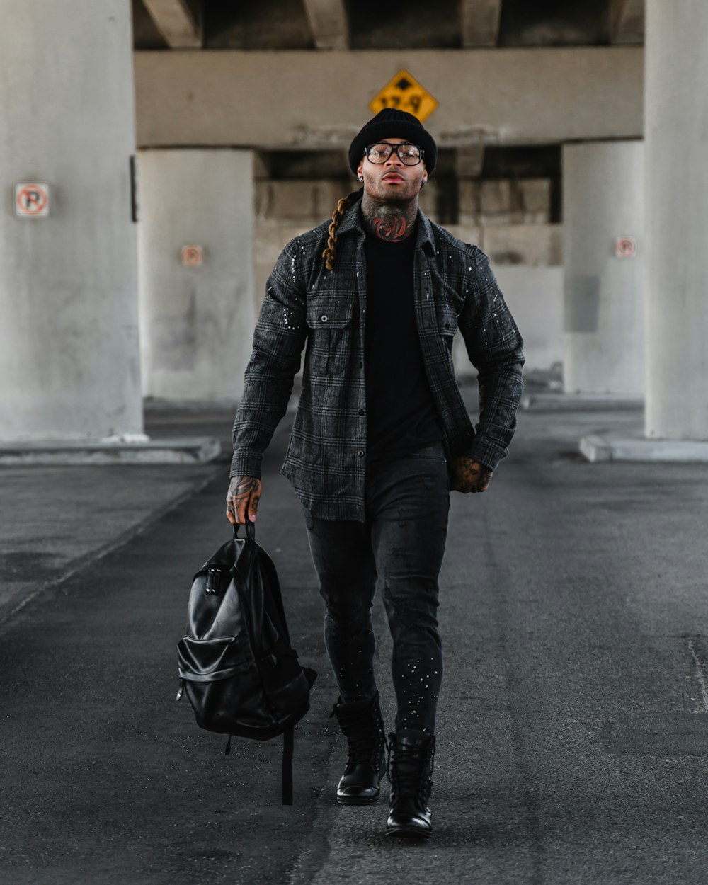 man in black leather jacket and yellow knit cap walking on street during daytime