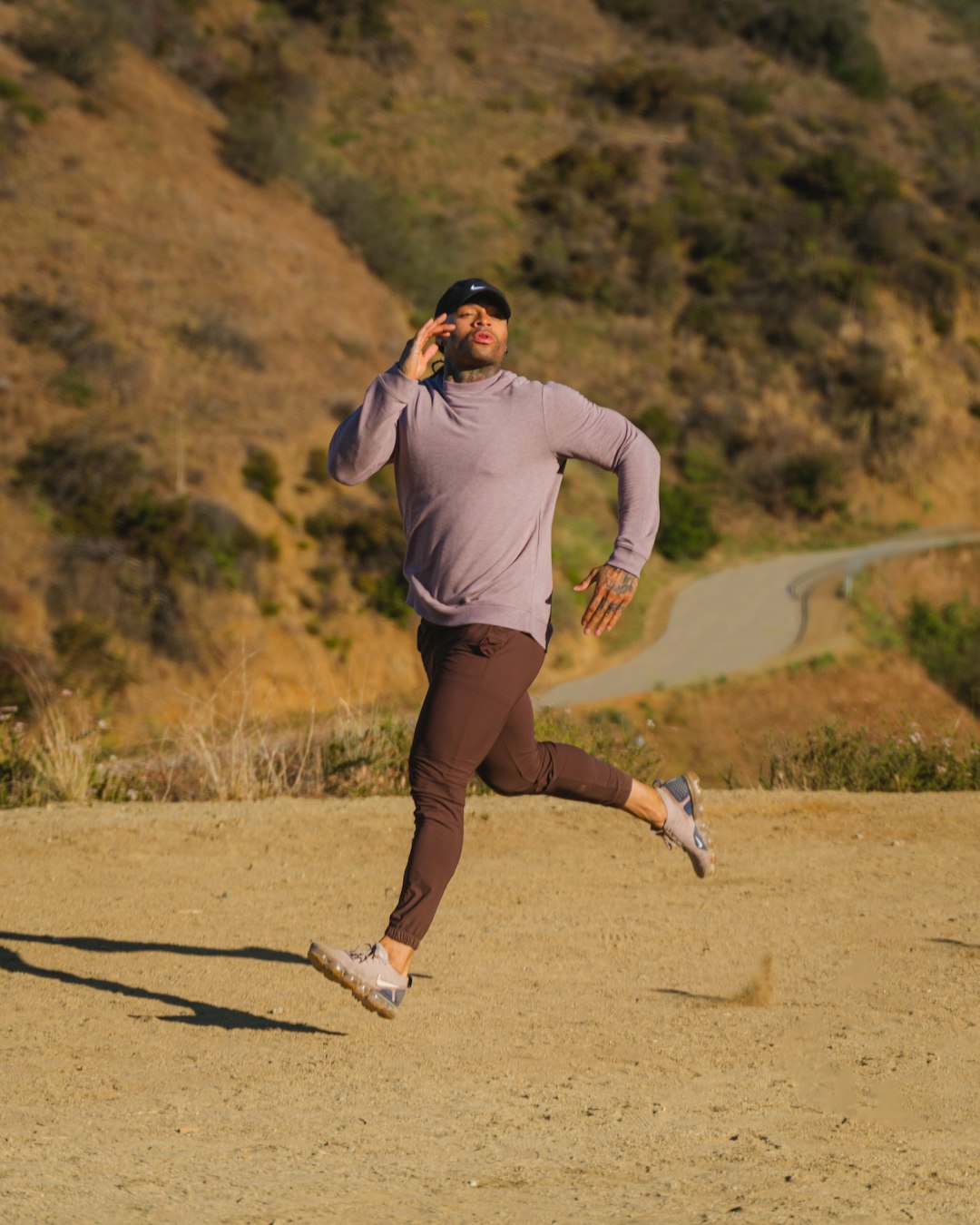man in gray long sleeve shirt and brown shorts running on brown sand during daytime