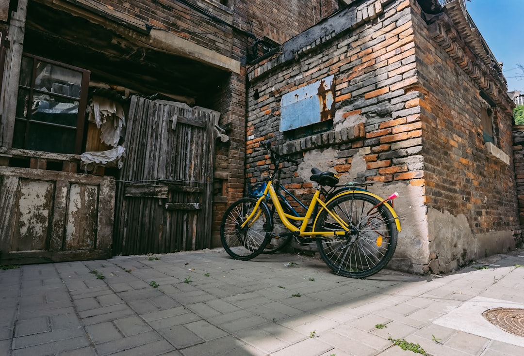 yellow and black bicycle parked beside brown brick wall