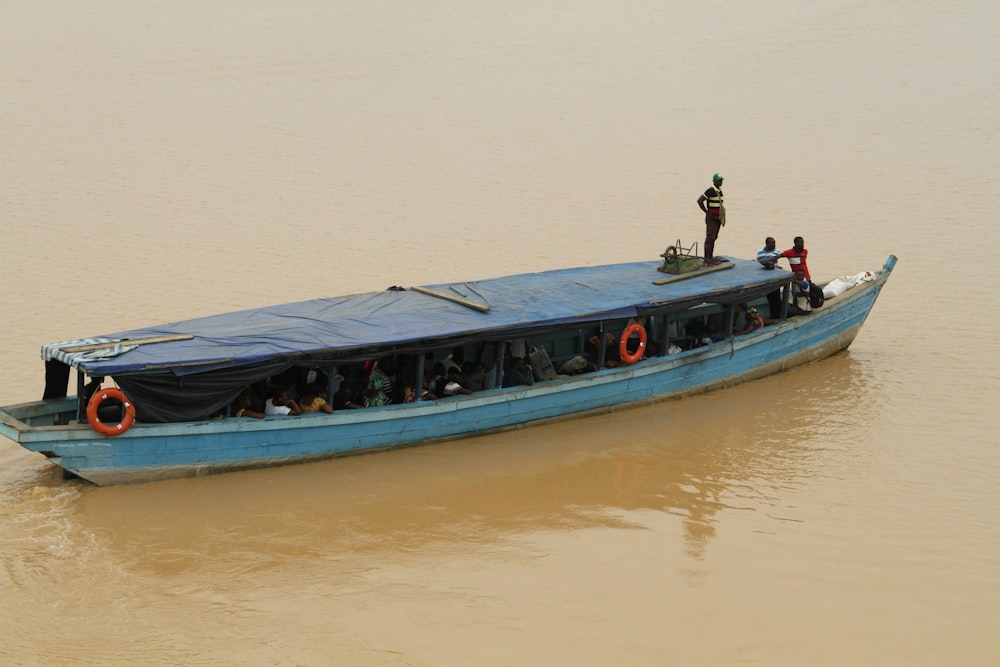 pessoas andando em barco azul e branco na água durante o dia