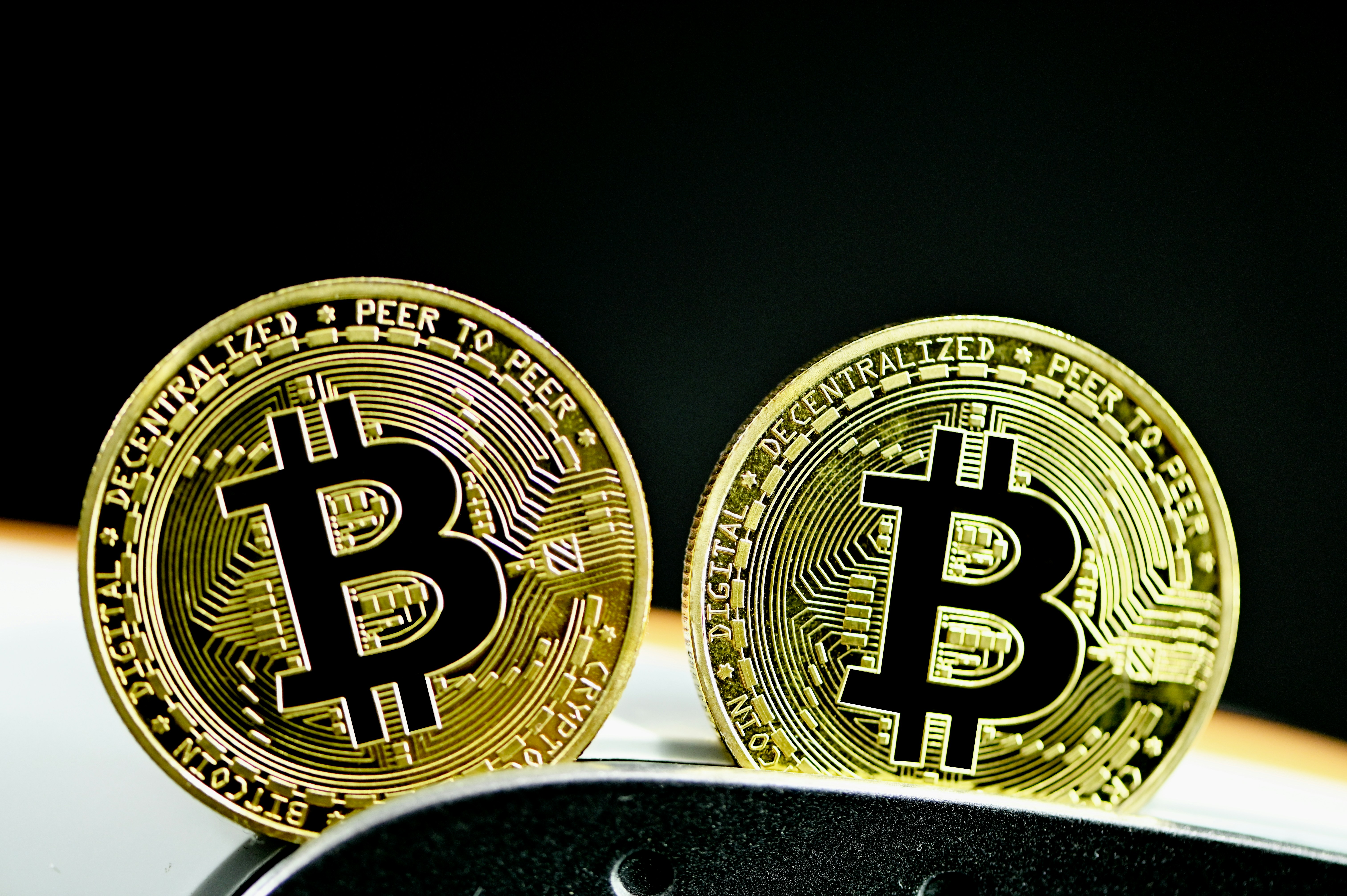 Two Bitcoins in front of a black and white contrasting background.