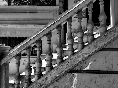 Photo of an old wooden staircase with faded finish and simple metal railing in a residential home.