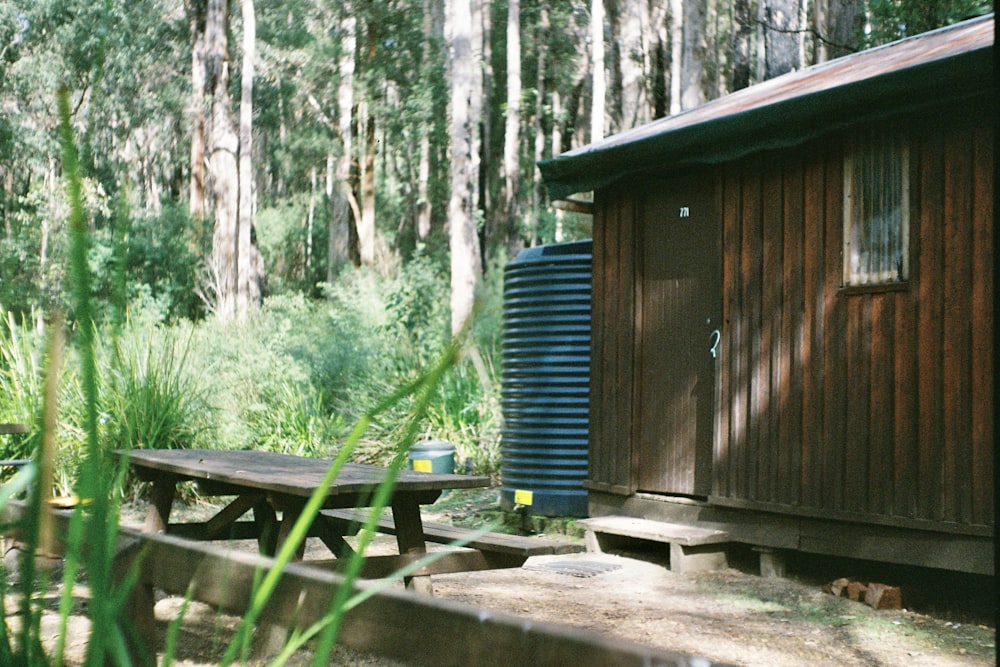 blue plastic barrels beside brown wooden house