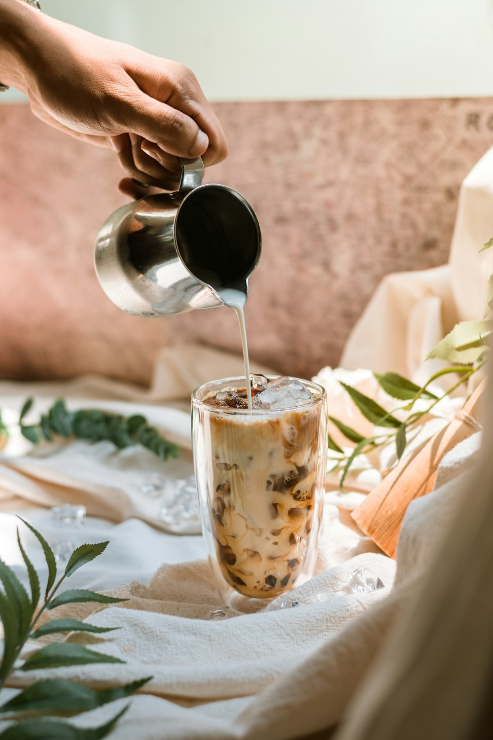 person pouring brown liquid on white and brown ceramic mug