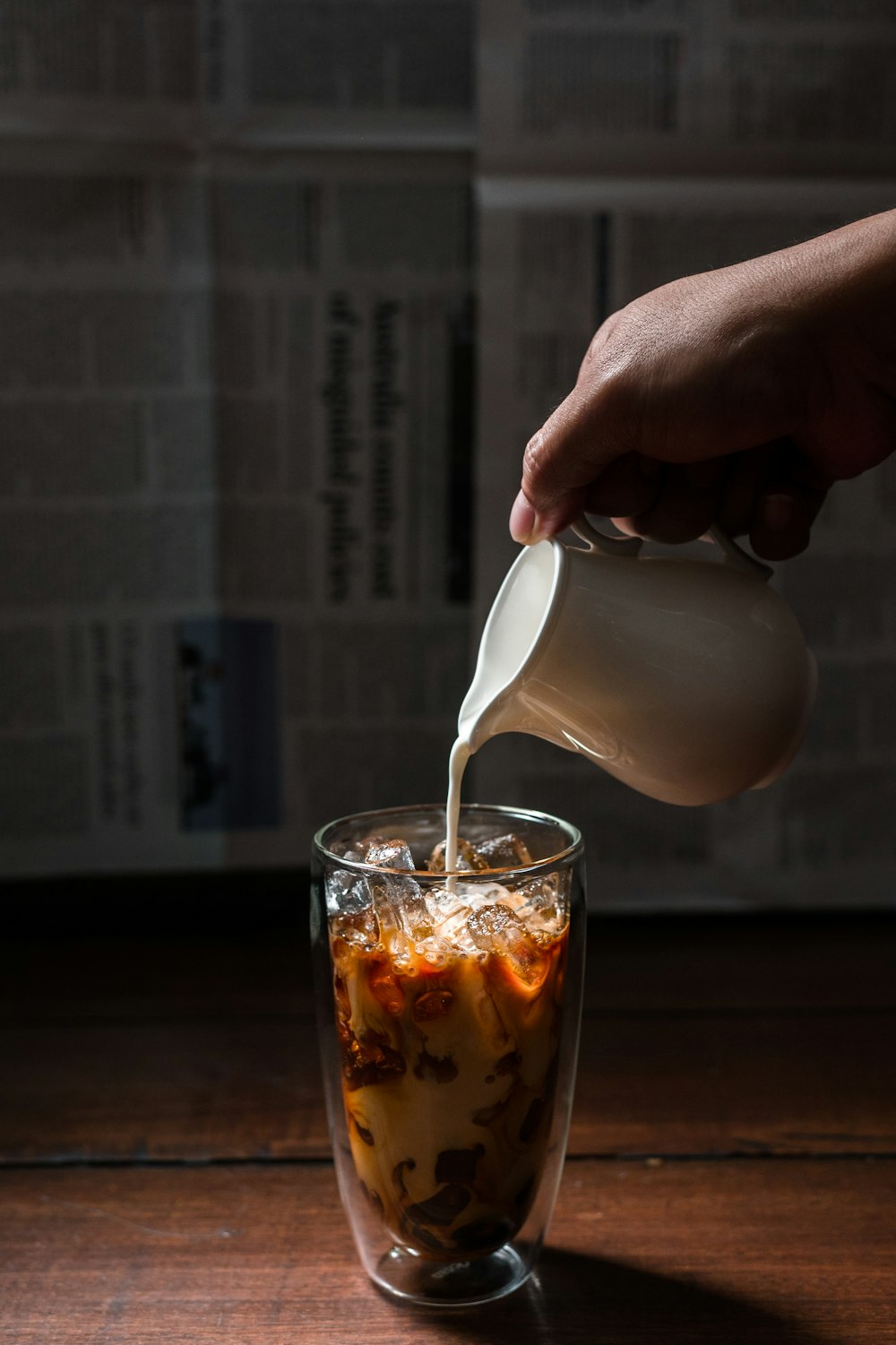 person pouring milk on clear drinking glass