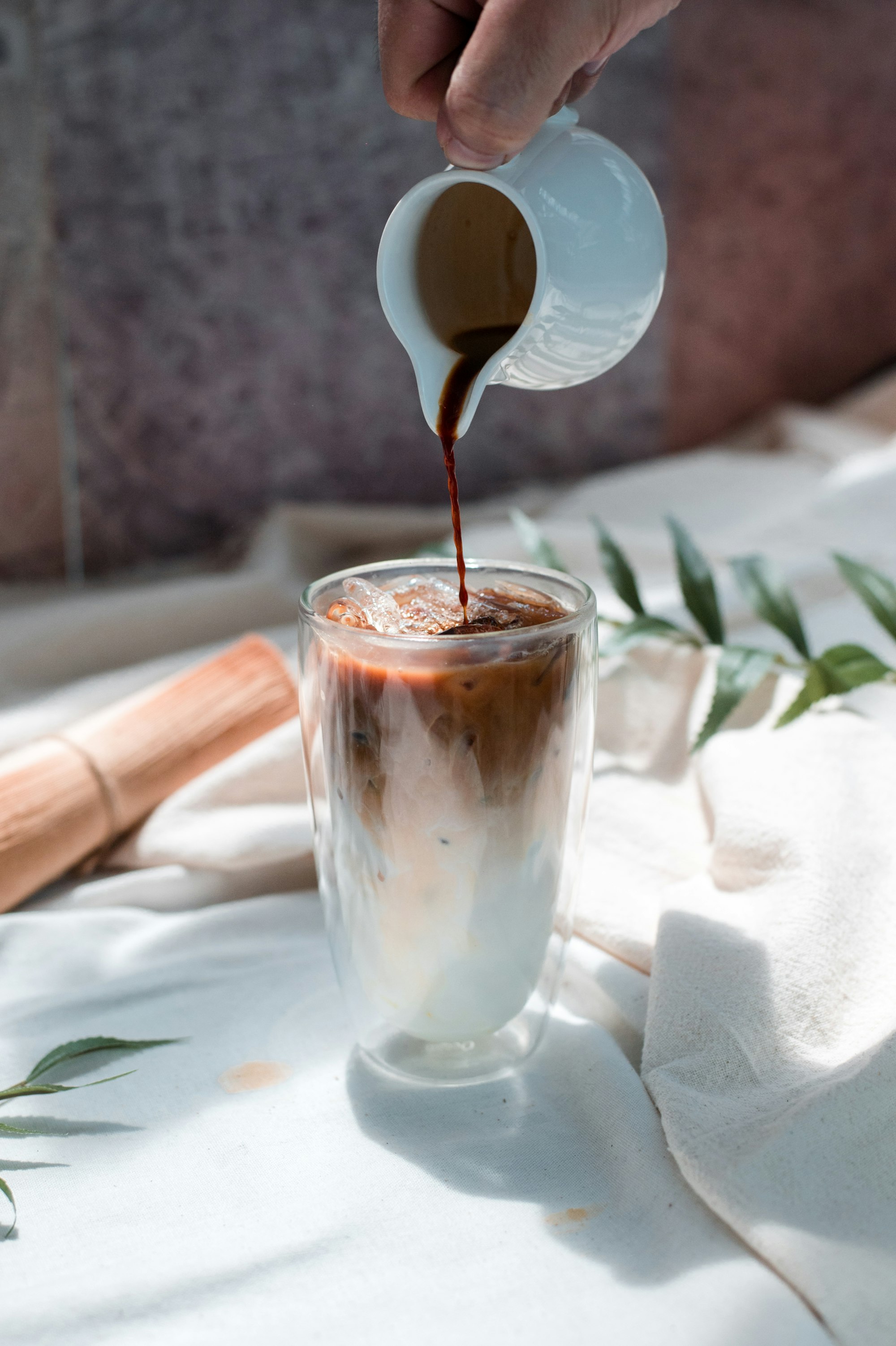 Barista pouring coffee into a glass of milk