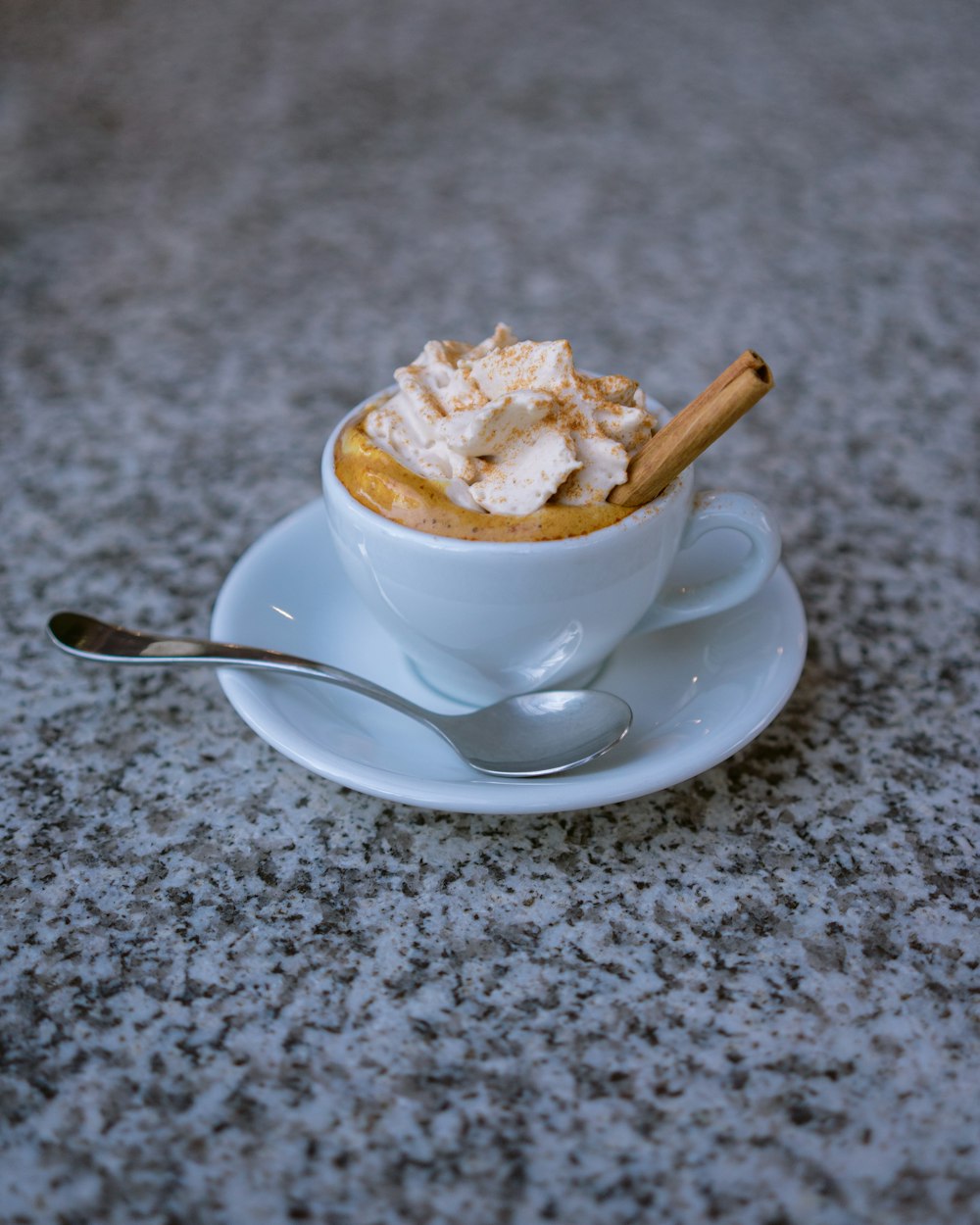 Tazza da tè in ceramica bianca con piattino su tessuto grigio