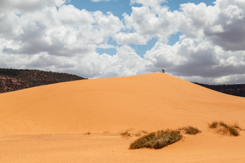 brown sand under white clouds and blue sky during daytime