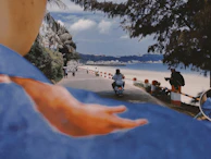 Scenic view of a scooter parked by a palm-lined coastal road, ready for island exploration.