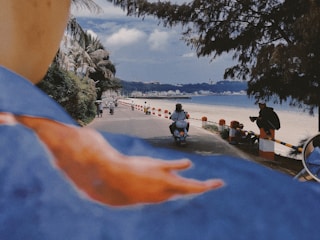 A traveler riding a Royal Enfield motorcycle along a scenic coastal road in Ranong, Thailand.