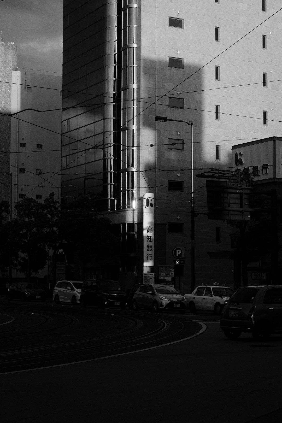 grayscale photo of cars parked near building