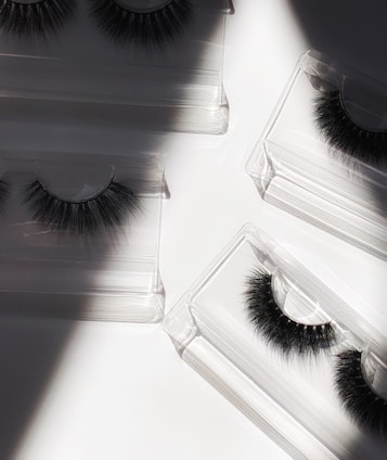 Dramatic, voluminous false eyelashes displayed on a sleek black surface