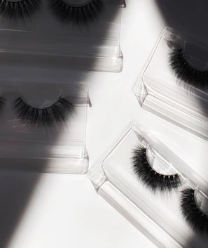 Elegant collection of false eyelashes displayed next to minimalist beauty tools